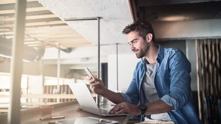 Blogbeitrag Xamarin Alternativen Detailbild Mann am Laptop mit Handy in der Hand